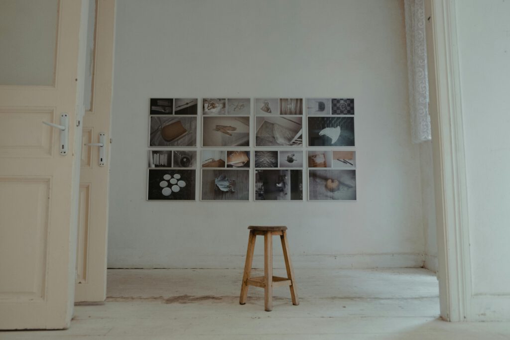 Artistic interior featuring wall art and a wooden stool in a minimalist room.